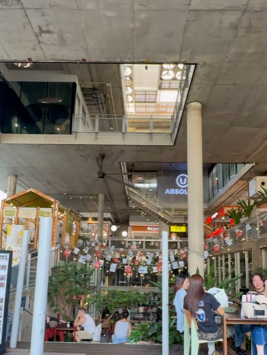 ภาพโถงเปิดโล่งของ The Commons Thonglor แสดงโครงสร้างคอนกรีต ช่องแสงด้านบน และมุมมองของพื้นที่หลายชั้น