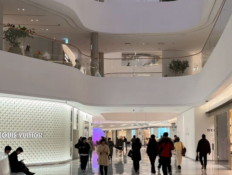 ทางเดินภายในและแนวหน้าร้านของ The Hyundai Seoul ที่เห็นทางสัญจรที่กว้าง ภาพรวมของหน้าร้าน และความเป็นระเบียบของพื้นที่